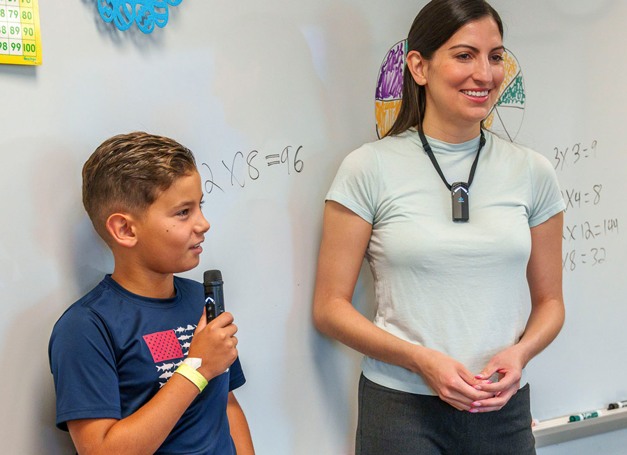 Teacher and student using wireless microphones in classroom for hearing augmentation